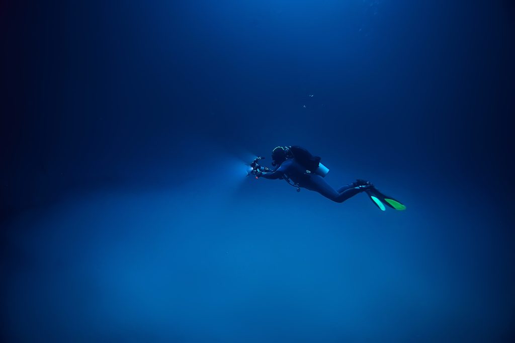 A scuba diver using a flashlight under water